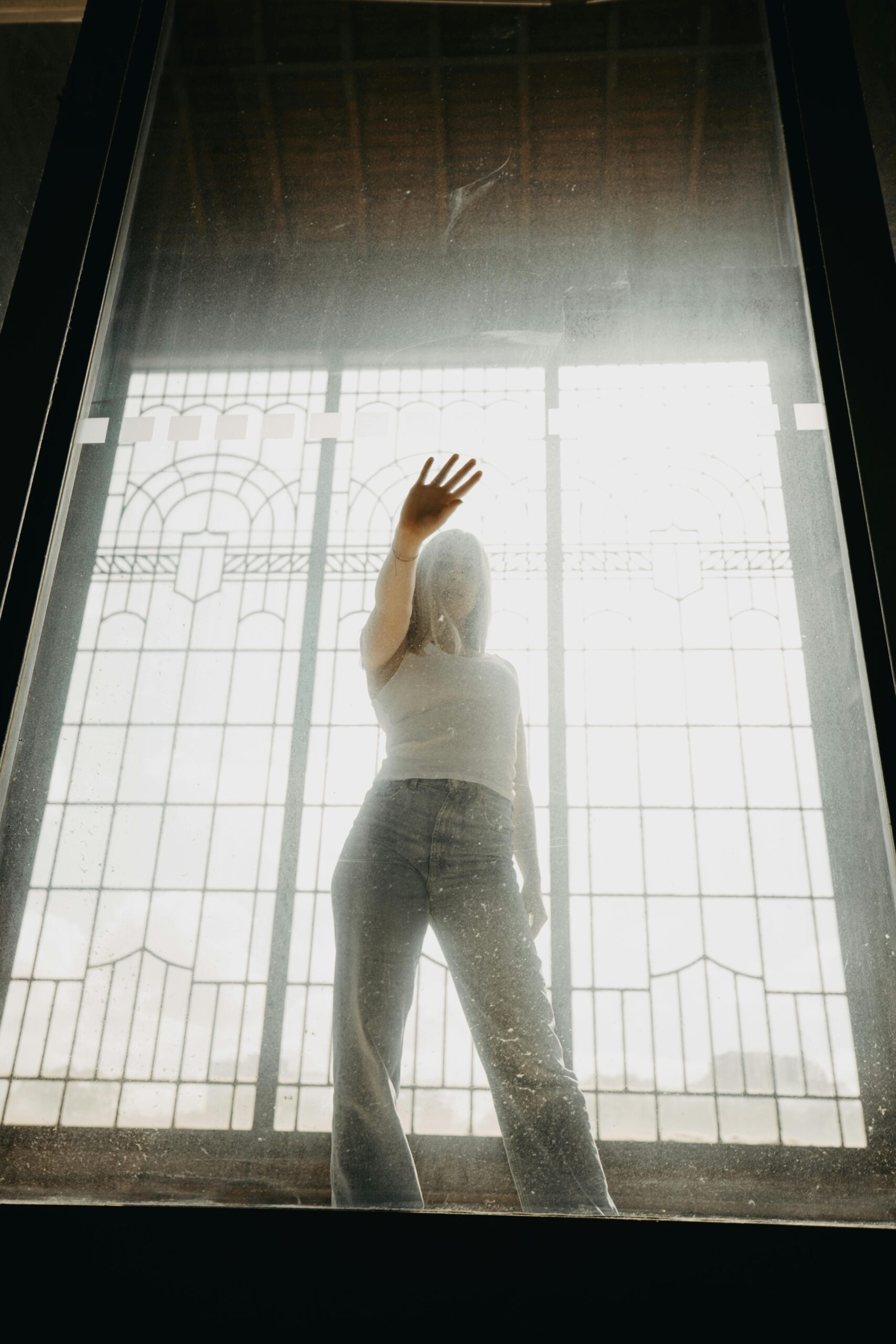 Woman standing behind a glass window touching it with her hand